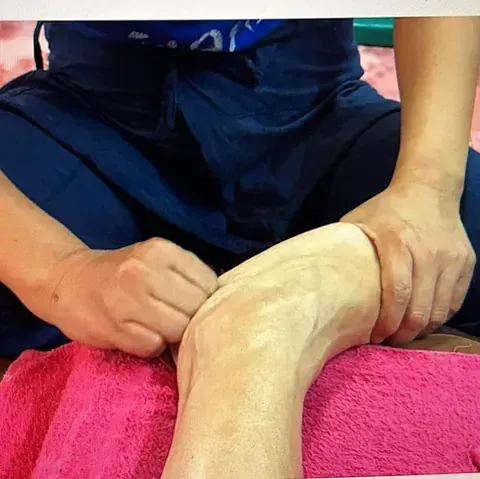 Una persona está sentada sobre una toalla rosa con las piernas cruzadas.