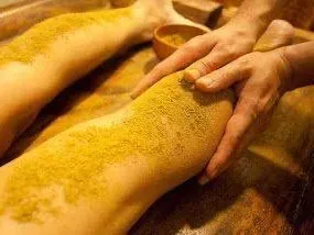Una persona está dando un masaje de piernas con polvo amarillo.