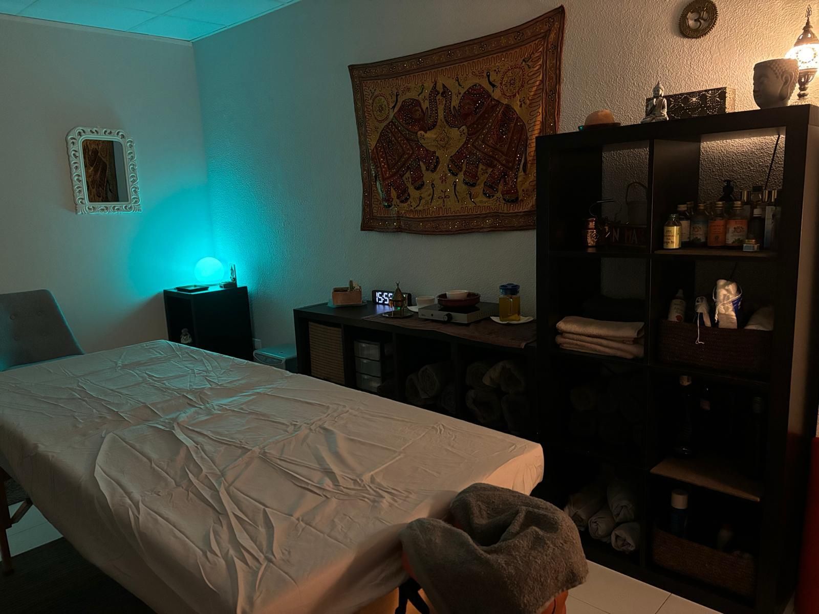 Una mesa de masajes en una habitación con un tapiz en la pared.