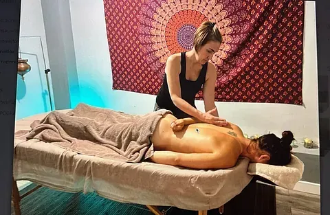 Una mujer le está dando un masaje a un hombre en una mesa de masajes.