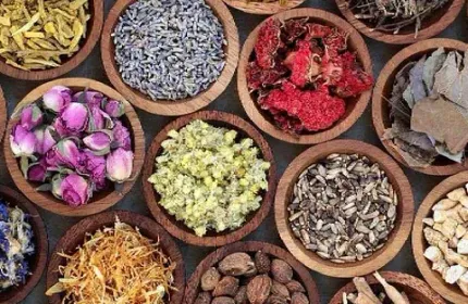 Una variedad de hierbas y flores secas en cuencos de madera sobre una mesa.