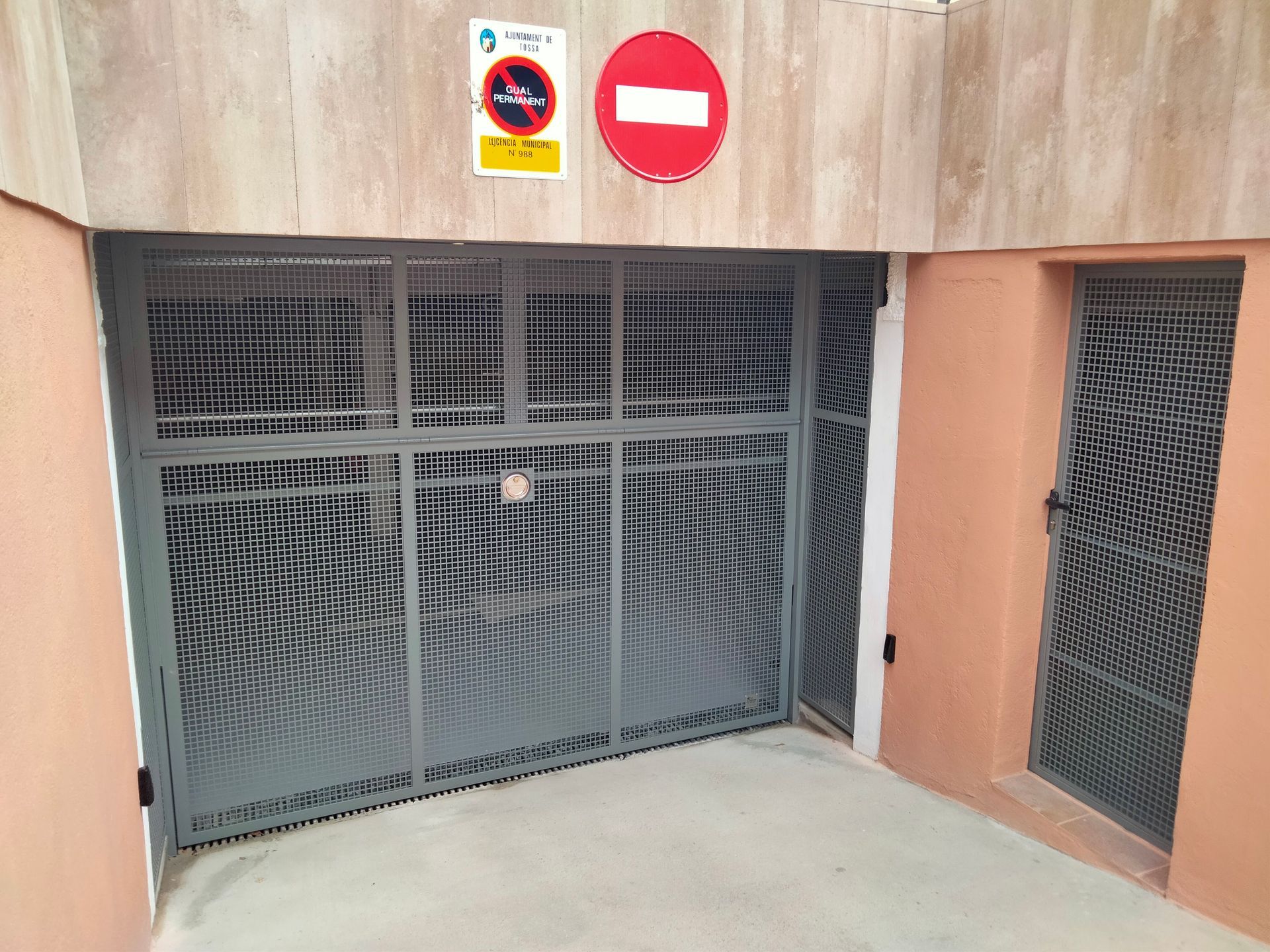 Entrada a un estacionamiento con puerta metálica y cartel de