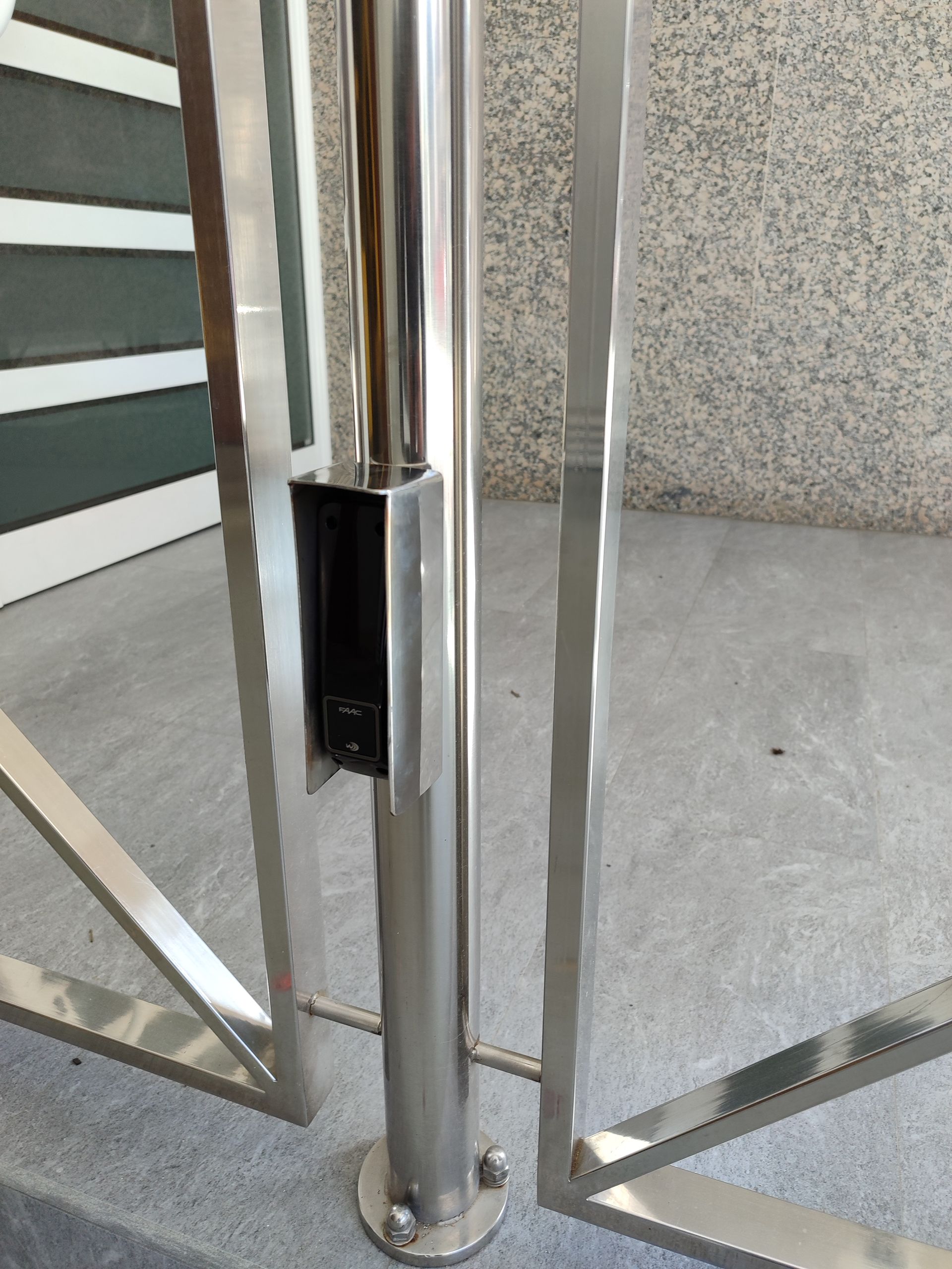 Torniquete de acero inoxidable. Poste central vertical con unidad de control de acceso rectangular.