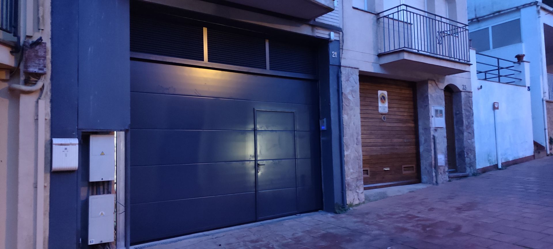 Una puerta de garaje azul oscuro en un edificio con un buzón blanco y una puerta de madera al lado.