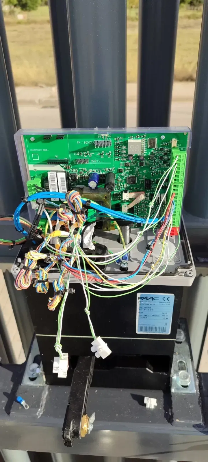 Caja de control abierta con placa de circuito y cableado, montada en un poste de metal.