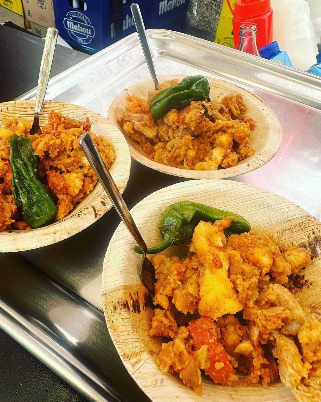 Hay tres tazones de comida con cucharas dentro sobre un mostrador.