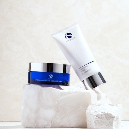 IS CLINICAL Hydra-Intensive Cooling Masque and Cleansing Complex, arrangiert auf weißen Steinblöcken vor einem Marmorhintergrund.