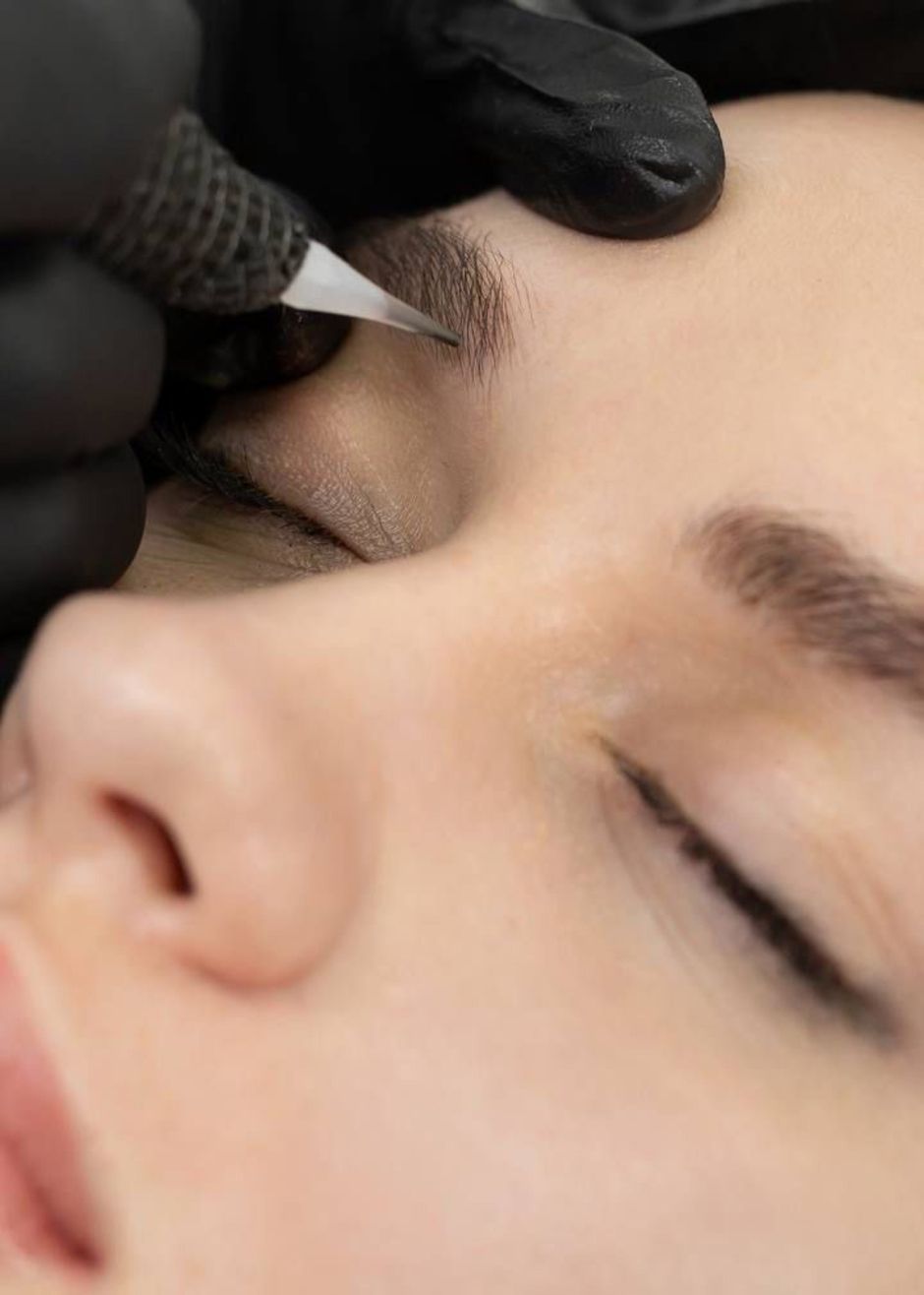 Nahaufnahme einer Person, die von einer Technikerin mit schwarzen Handschuhen eine kosmetische Lippentätowierung erhält.