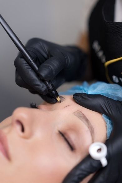 Eine Person mit weißen Handschuhen führt an einer Kundin eine Dermaplaning-Gesichtsbehandlung mit einer kleinen Skalpellklinge durch.