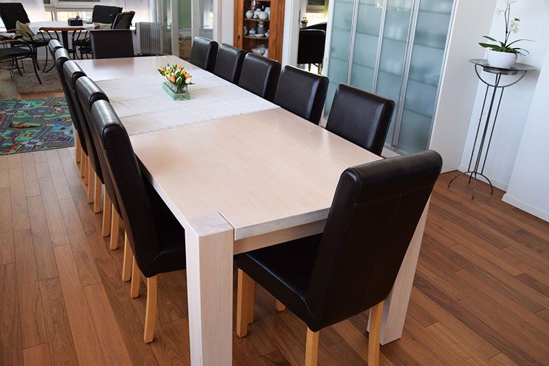 Ein langer weißer Tisch mit schwarzen Stühlen in einem Raum