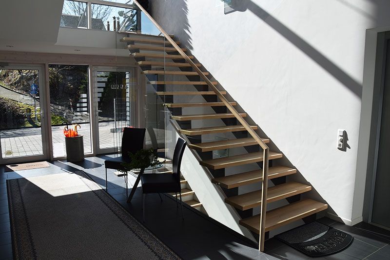 Eine Treppe mit Holzgeländer führt in den zweiten Stock eines Hauses.