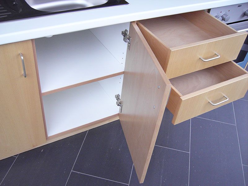 Ein Küchenschrank mit offener Tür und zwei offenen Schubladen