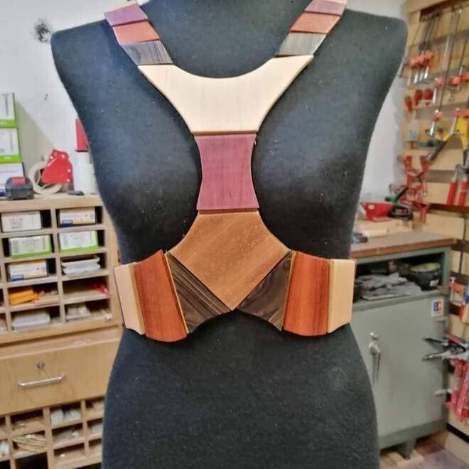 Arnés de pecho de madera de colores sobre un maniquí negro en un taller.