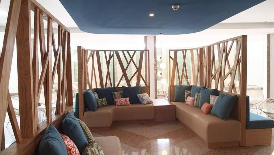 Salón moderno con sofás color canela, cojines coloridos y ventanas de celosía de madera con vistas al agua.
