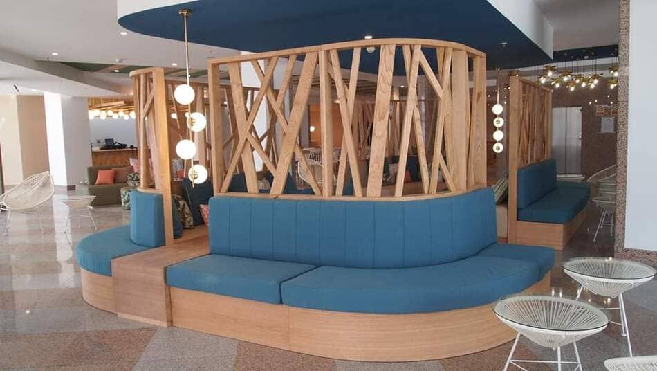 Bancos curvos de color azul rodeando un separador de celosía de madera en una zona de estar moderna.