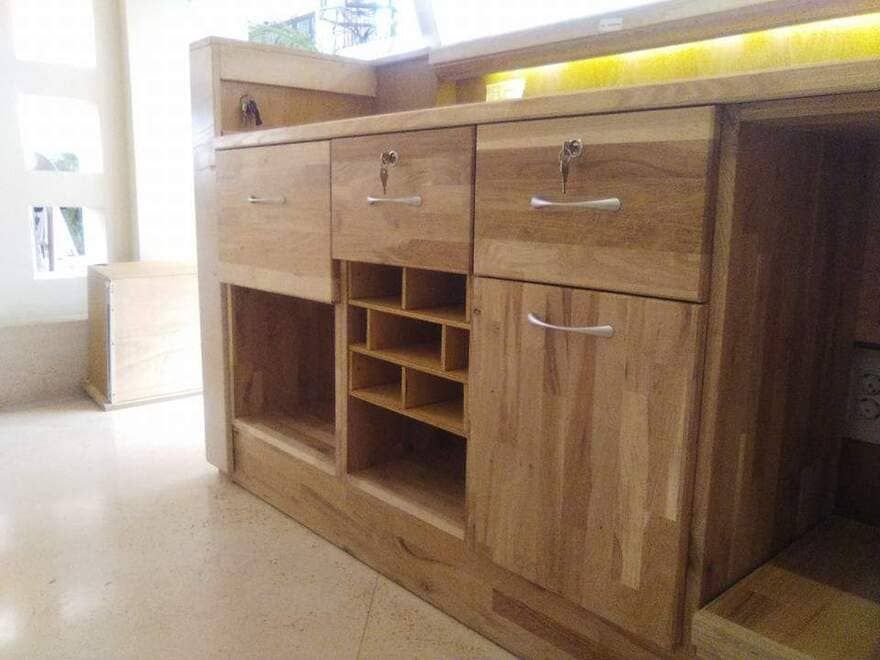 Mueble de baño de madera con cajones, puertas de armario y estante para toallas en una habitación luminosa.