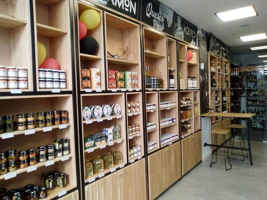 Estanterías con tarros, botellas y productos envasados en un pequeño pasillo de una tienda o mercado.