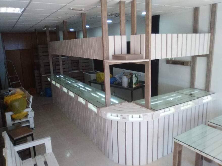 Cafetería interior vacía con mostradores de cristal y paredes revestidas de paneles de madera a rayas.
