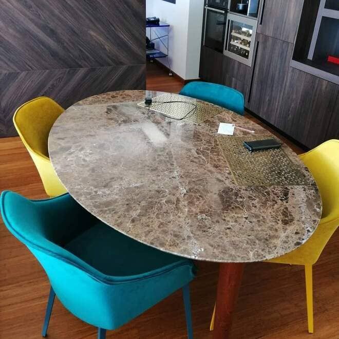 Mesa de comedor moderna para cocina con cuatro sillas coloridas y tablero ovalado con diseño de mármol.