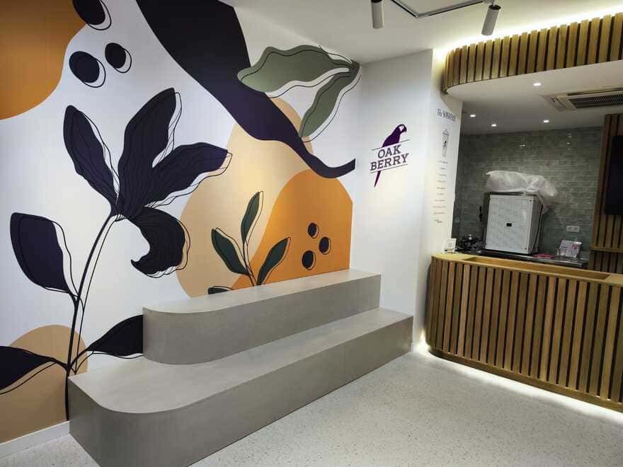 Vestíbulo moderno con mural, banco gris y mostrador de recepción de madera bajo iluminación cálida.