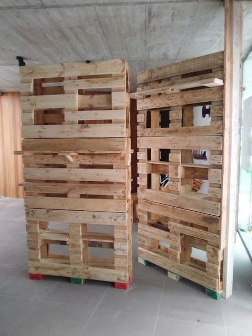 Palets de madera apilados contra una pared en un almacén interior.