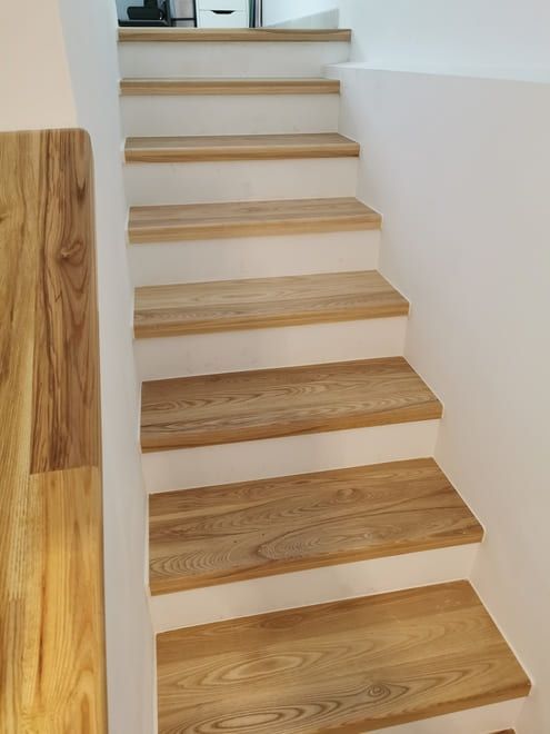 Escalera de madera con paredes y escalones de color claro que conducen al interior.