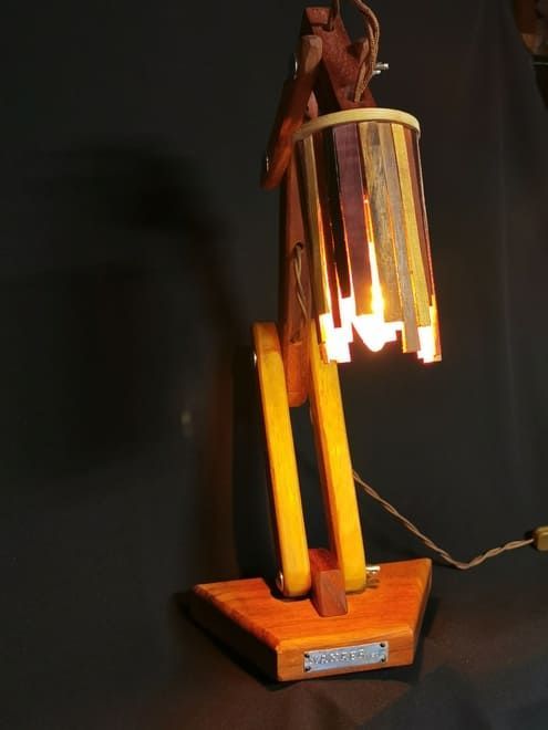 Lámpara de escritorio de madera con pantalla cilíndrica luminosa sobre fondo negro.