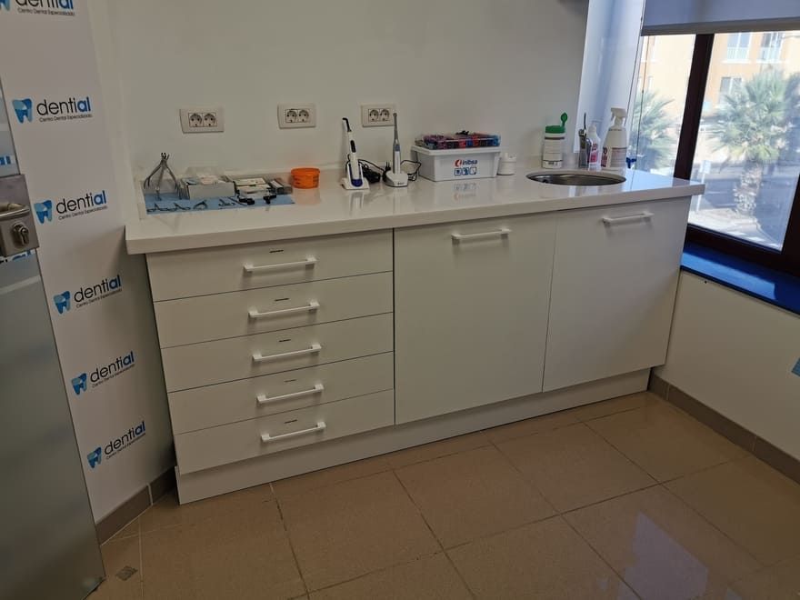 Encimera de clínica con cajones, lavabo y suministros médicos en una habitación luminosa.
