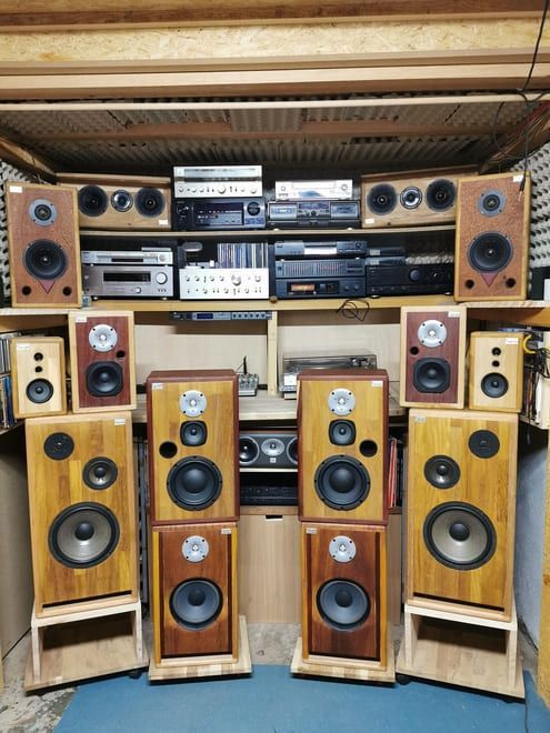 Una pared con altavoces y componentes de audio antiguos dispuestos como en un equipo de música doméstico.