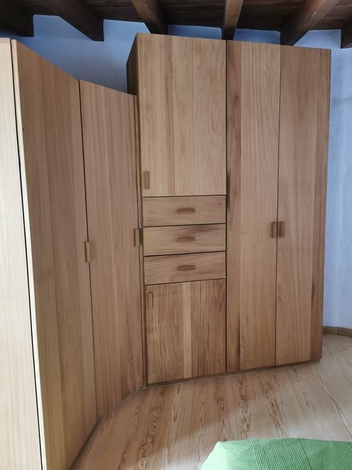 Armario de madera con cajones centrales y compartimentos en una habitación con suelo de madera noble.