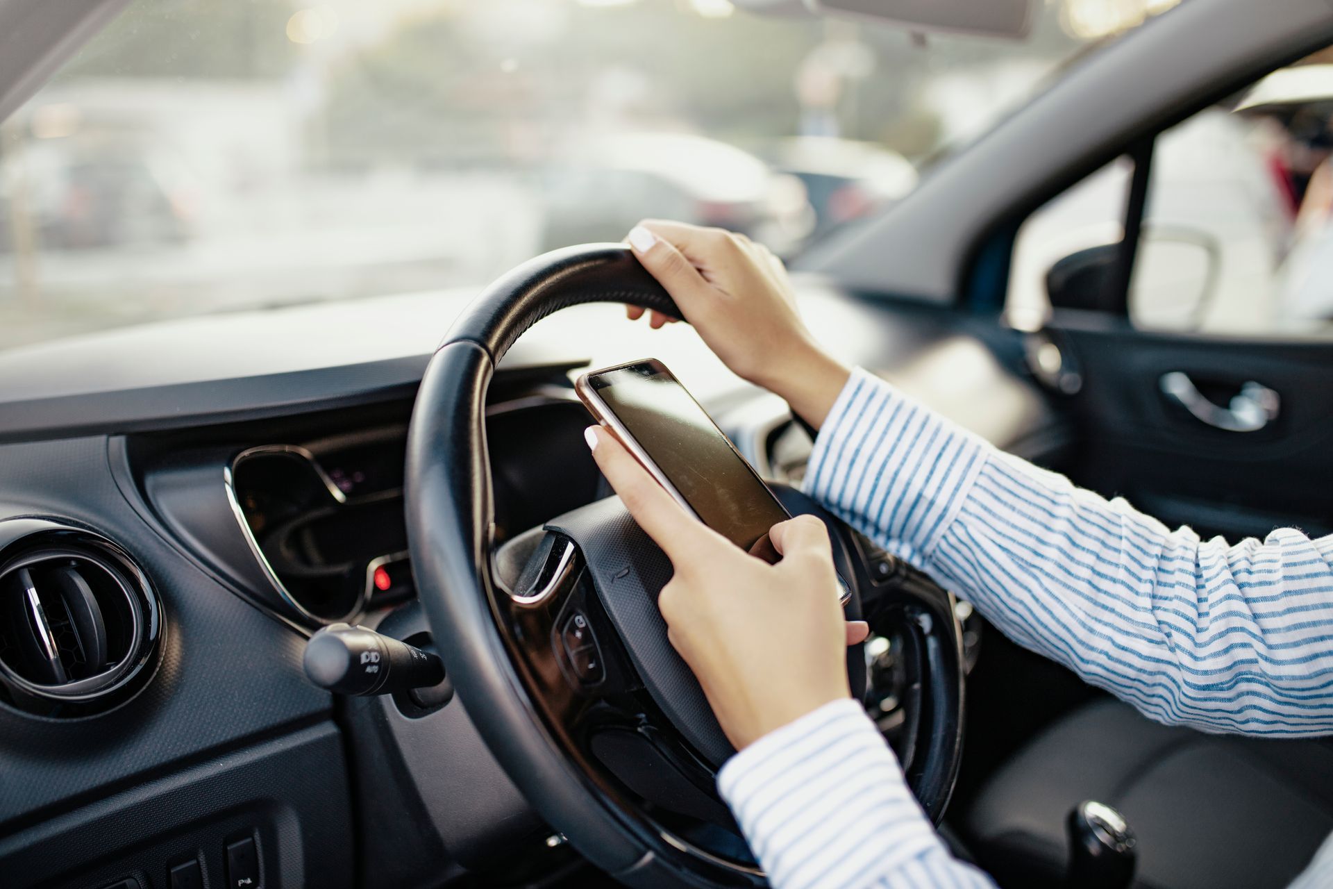 Une femme au volant d'une voiture, sur son téléphone