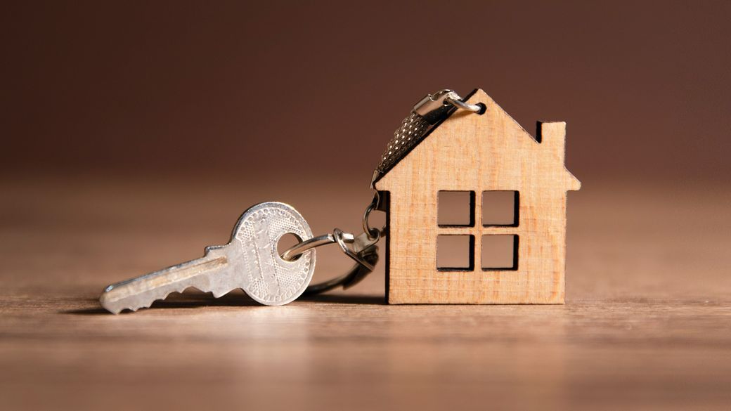 Une clé avec un porte-clés en forme de maison en bois