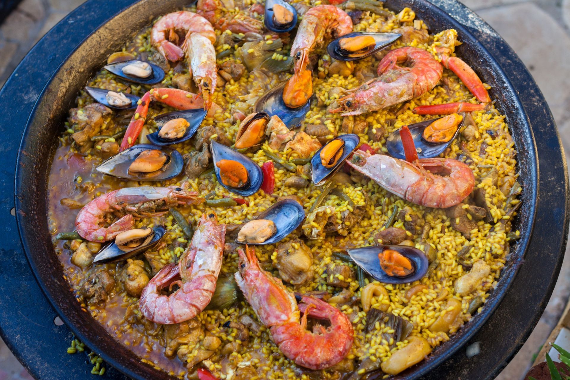 Paella con camarones, mejillones y arroz amarillo en una sartén grande.