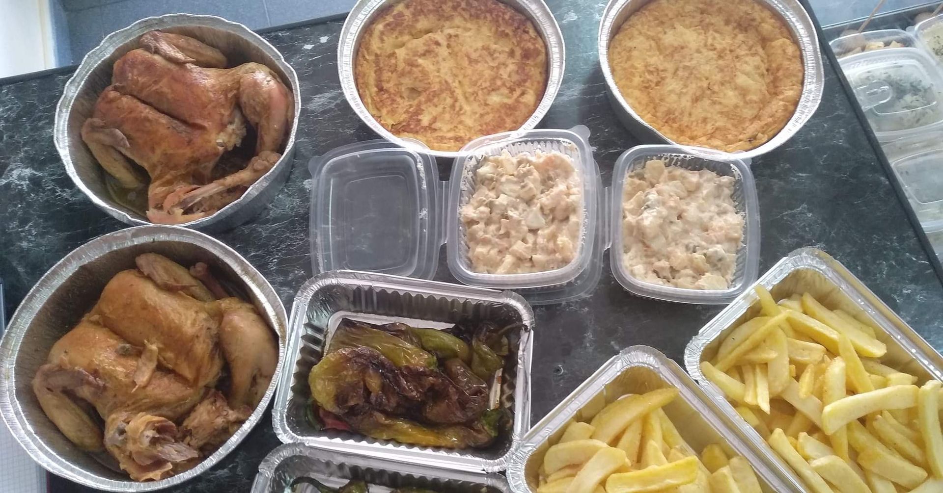 Comidas preparadas en envases de aluminio: pollo, guisos, patatas fritas y pimientos.