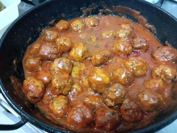 Albóndigas en una salsa de tomate rojo vibrante en una sartén negra, listas para servir.