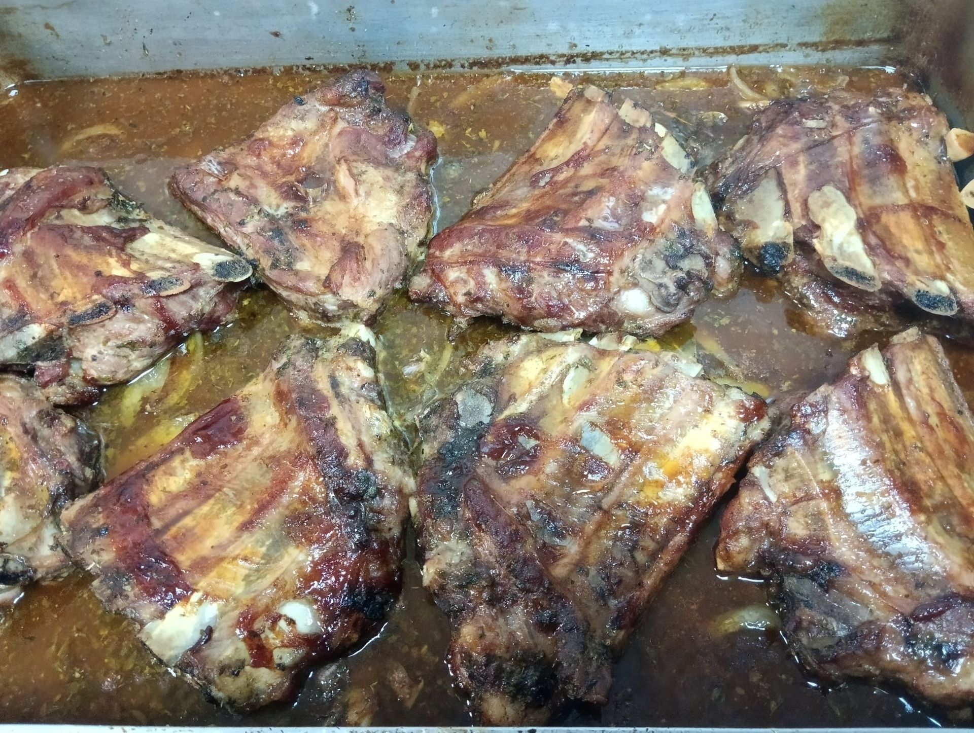 Costillas cocidas en sartén con salsa y cebolla.