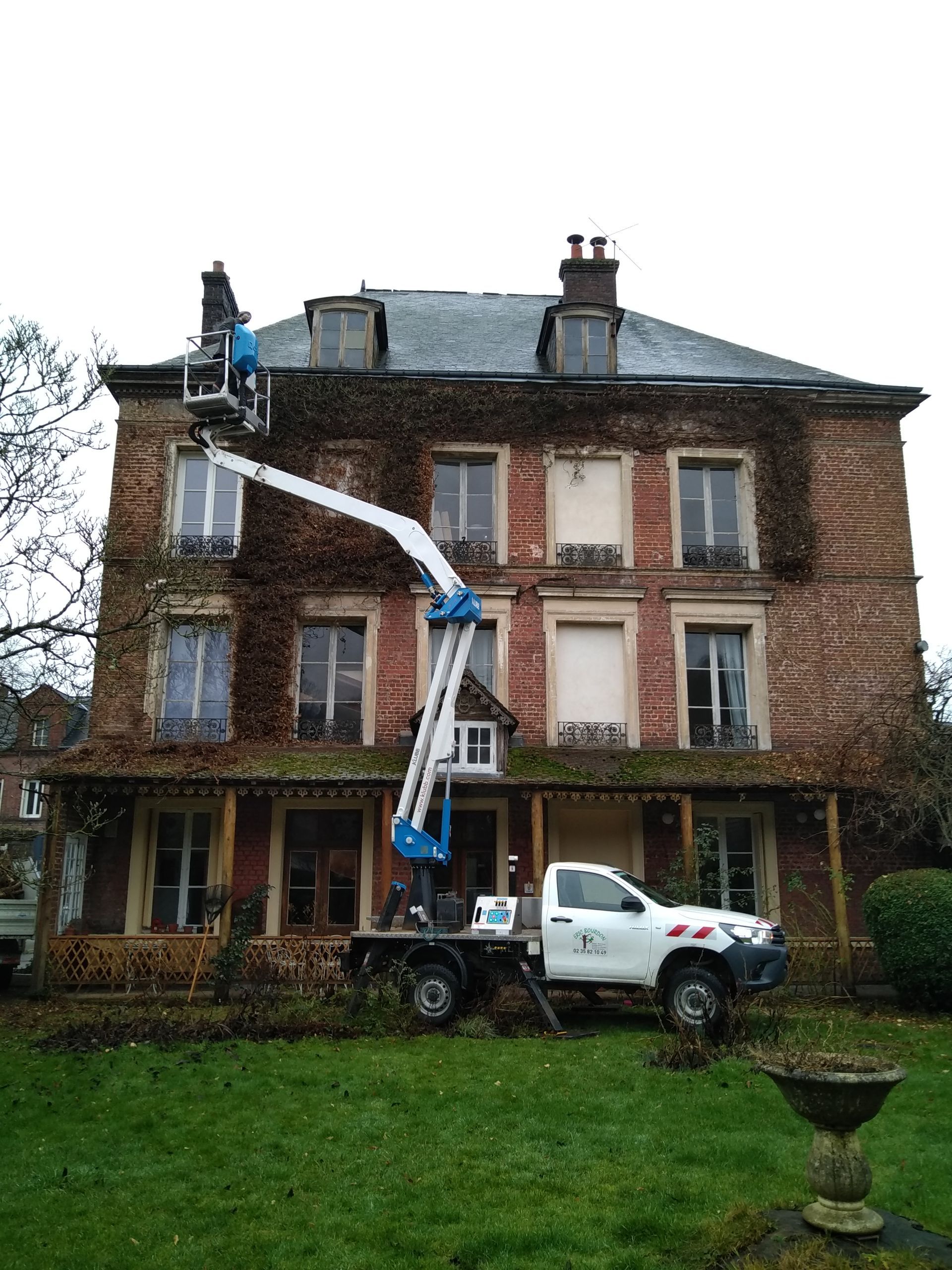 Photo d'un camion avec nacelle devant une maison