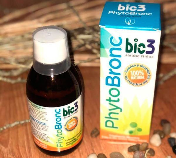 Una botella de fitobronc se encuentra junto a una caja en una mesa de madera.