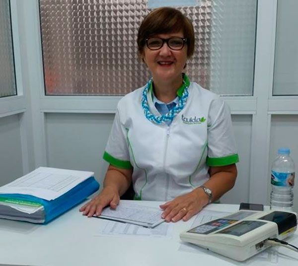 Una mujer con gafas está sentada en un escritorio frente a una ventana.