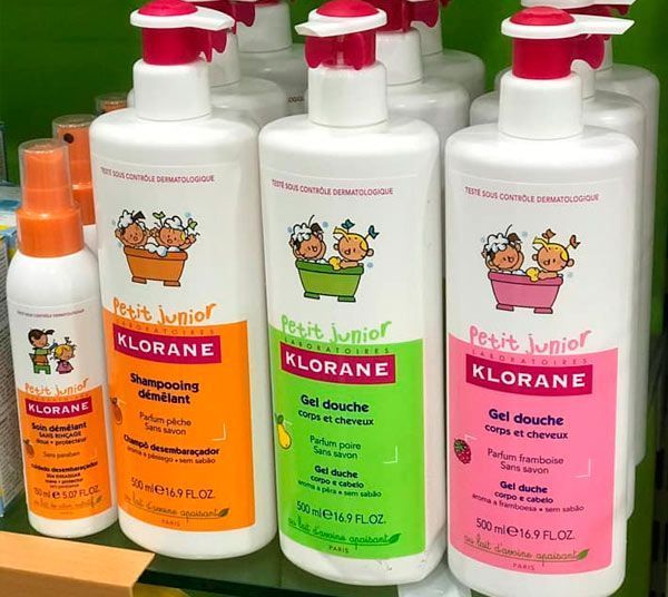 Varias botellas de productos Klorane están alineadas en un estante.