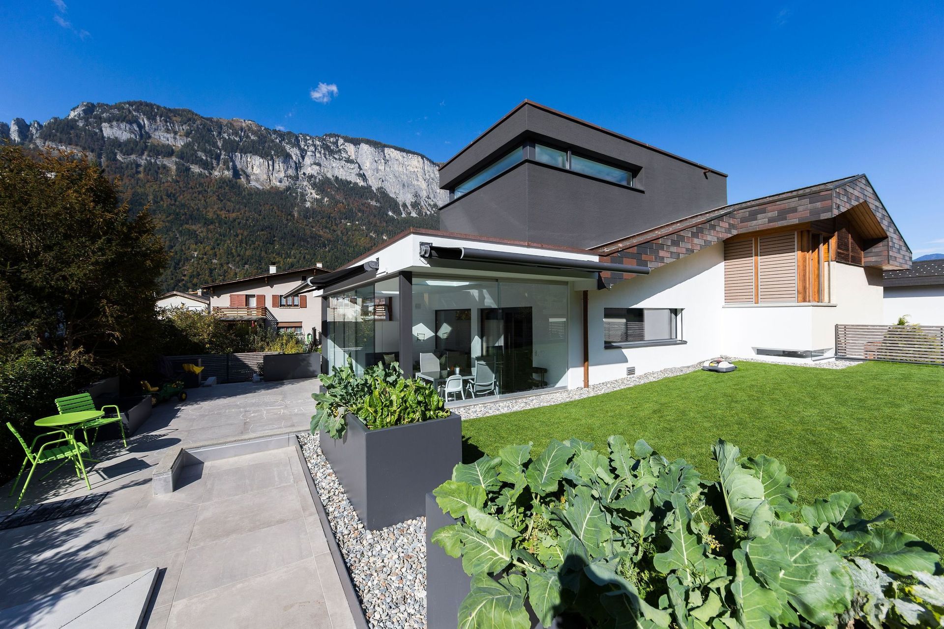 Ein modernes Haus mit einer großen Wiese und Bergen im Hintergrund