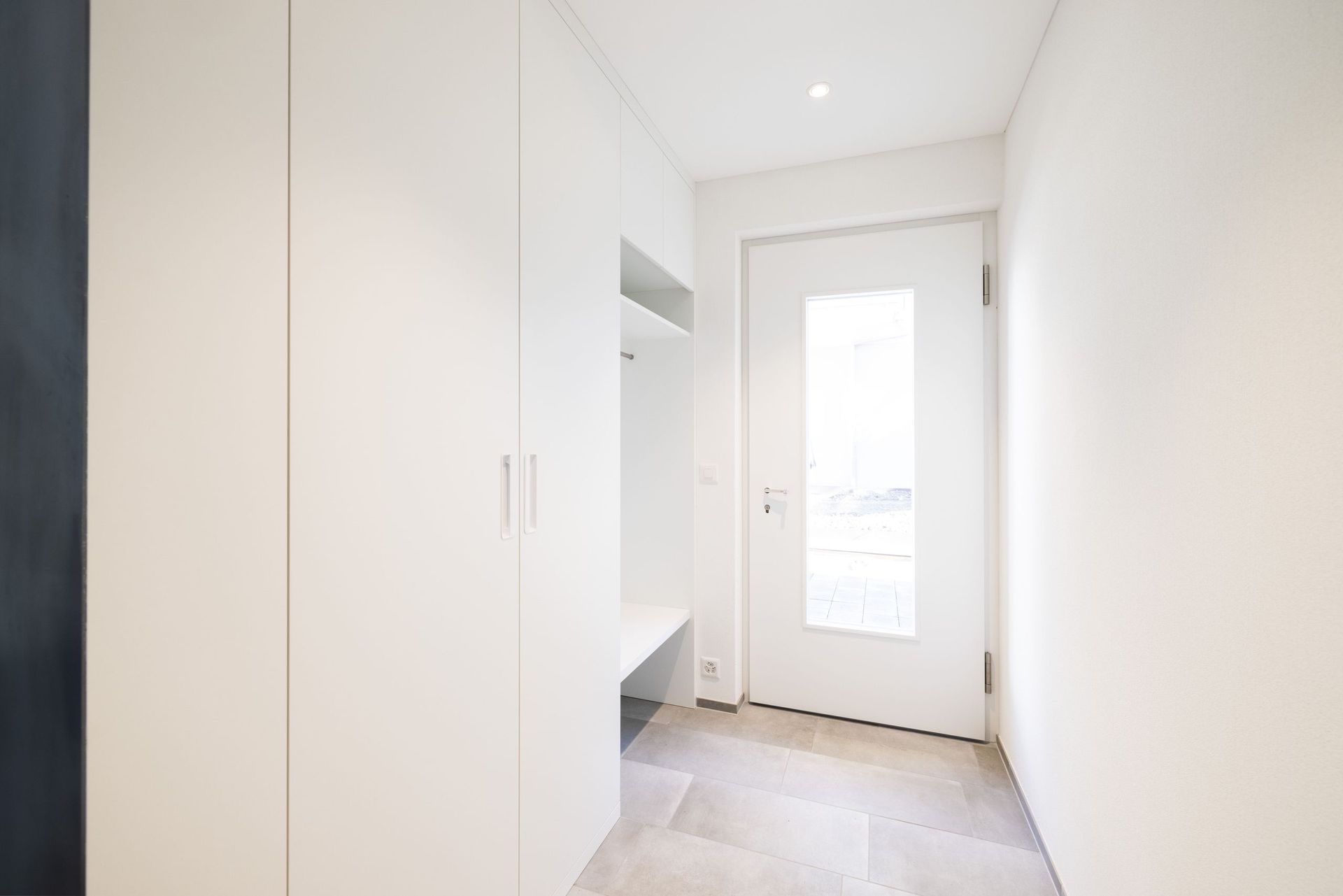 Ein Flur mit einer weißen Tür und einem Fenster.