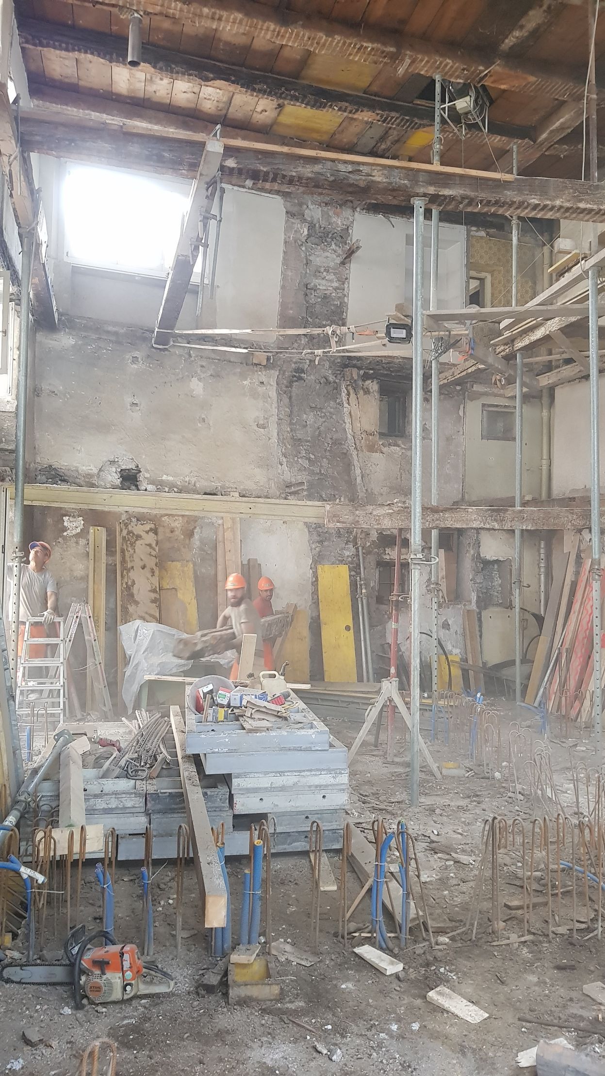 Mitten im Raum wird ein Gebäude mit einer Kettensäge abgerissen.