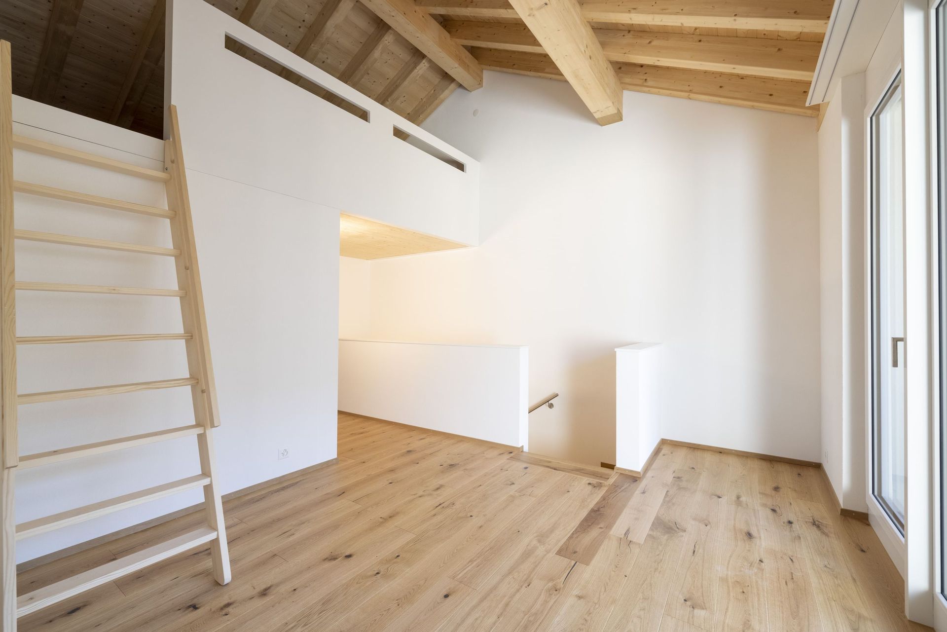 Ein leerer Raum mit Holzboden und einer Holzleiter.