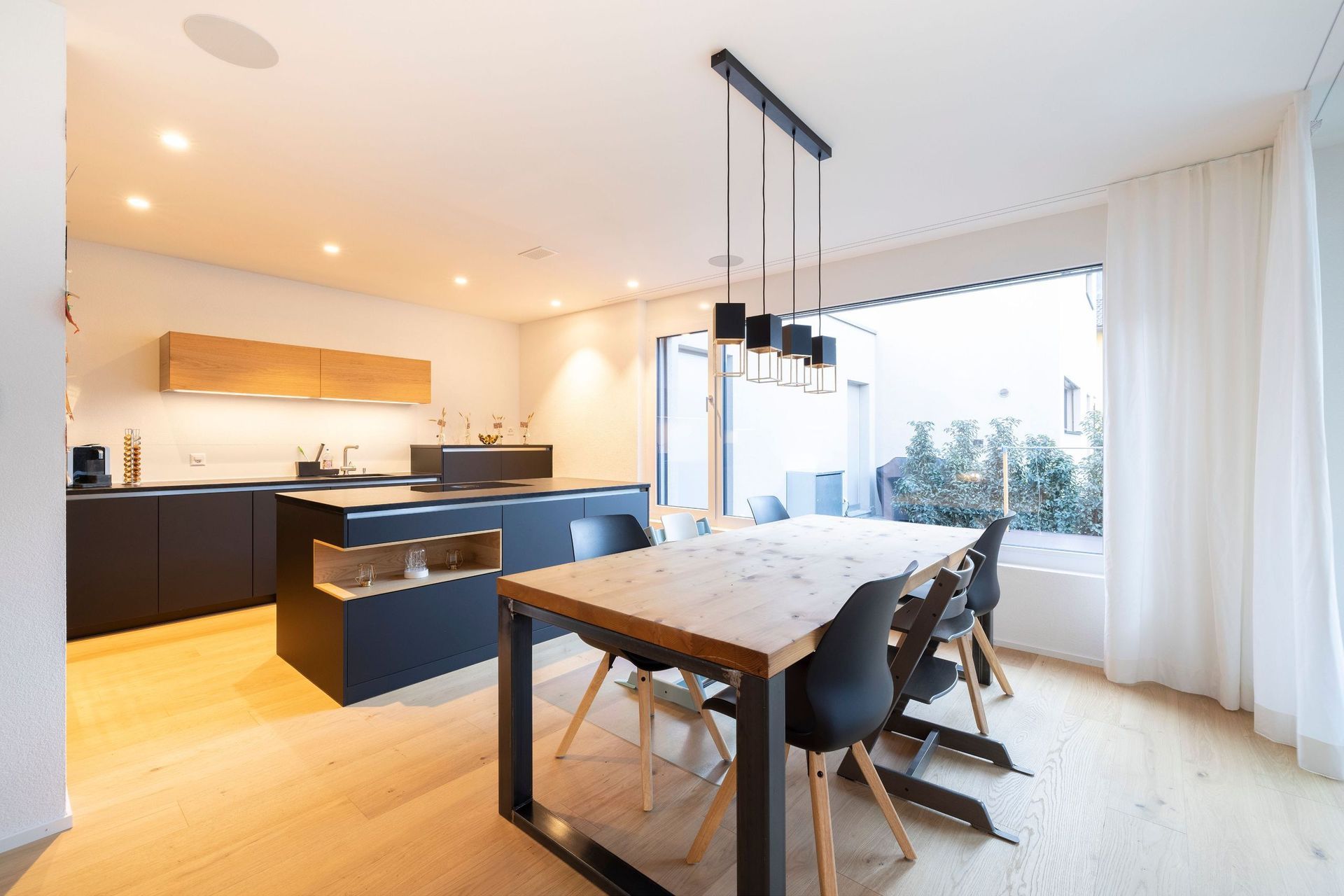 Ein Esstisch und Stühle in einer Küche mit einem großen Fenster.