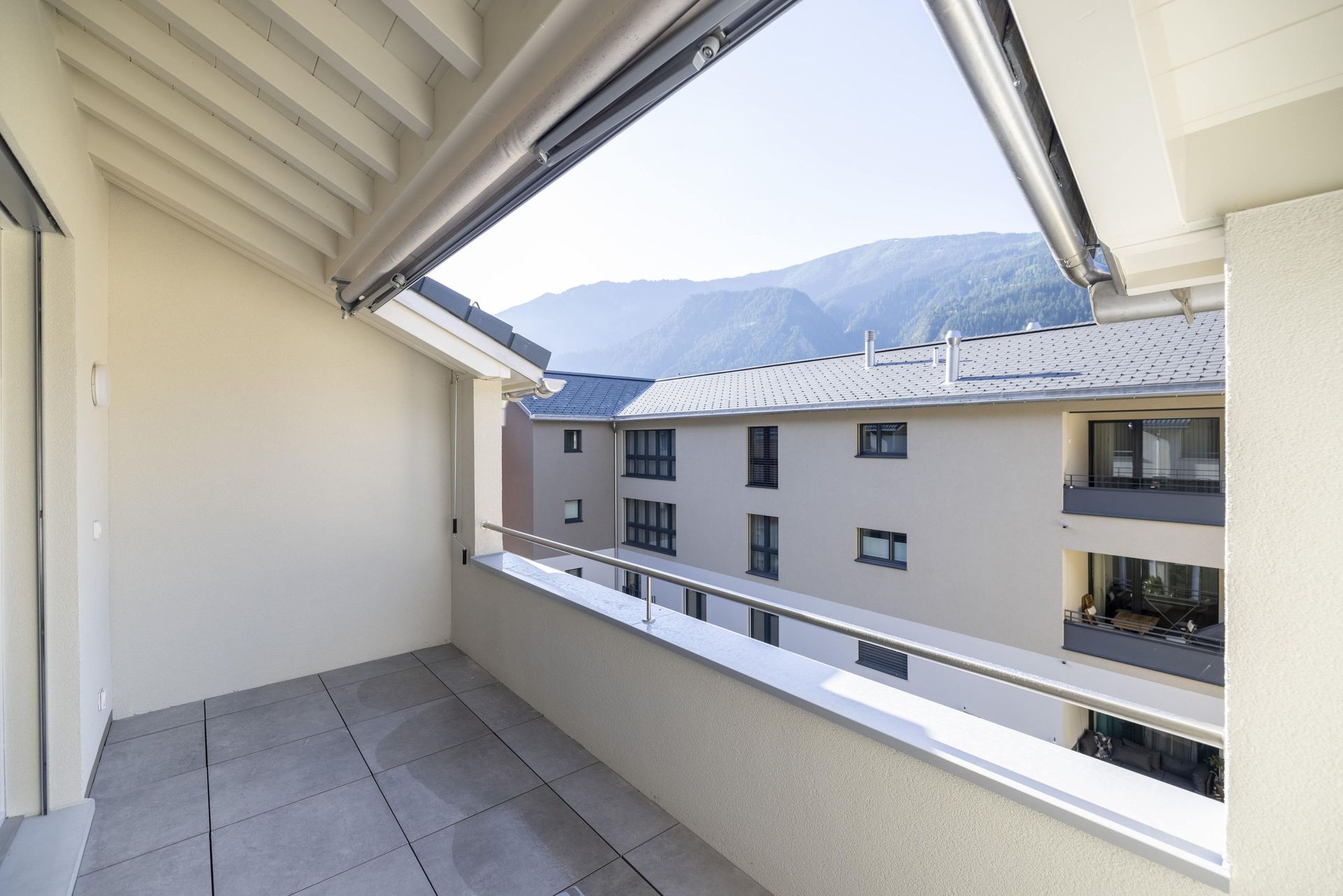 Ein leerer Balkon mit Blick auf die Stadt und die Berge.