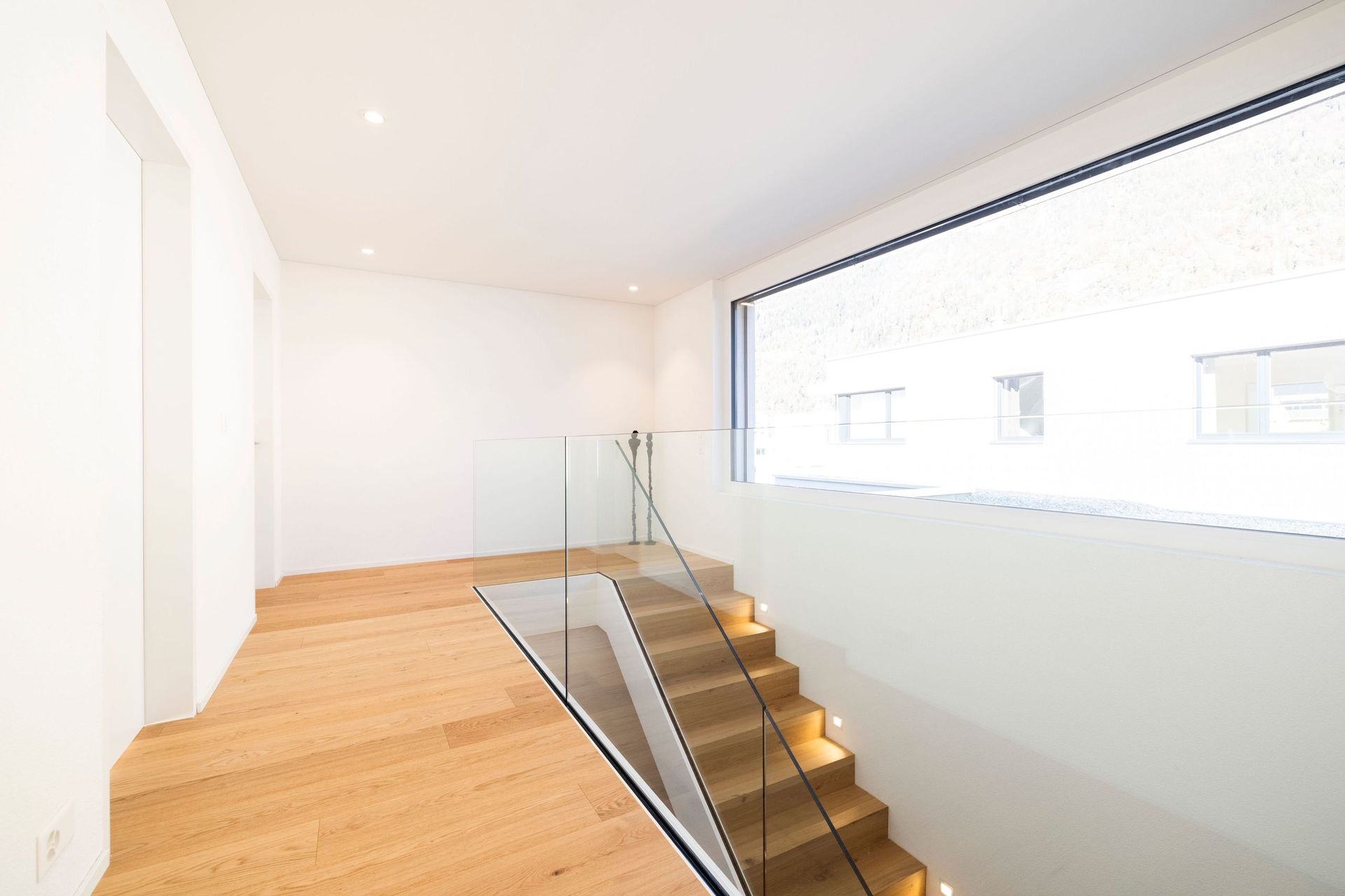 Es gibt eine Treppe mit Glasgeländer und großem Fenster.