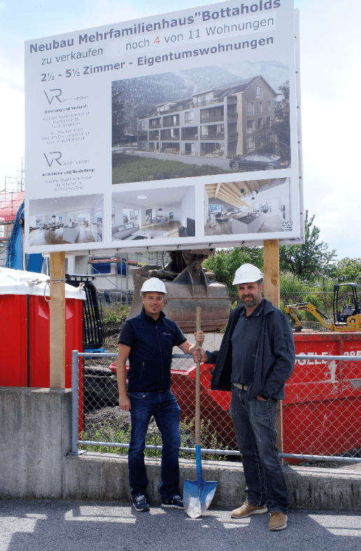 Zwei Männer stehen vor einem Schild mit der Aufschrift