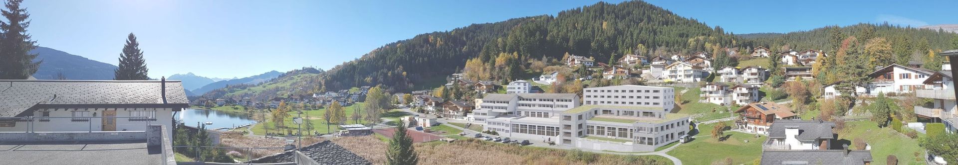 Ein verschwommenes Bild einer Stadt mit Bergen im Hintergrund.