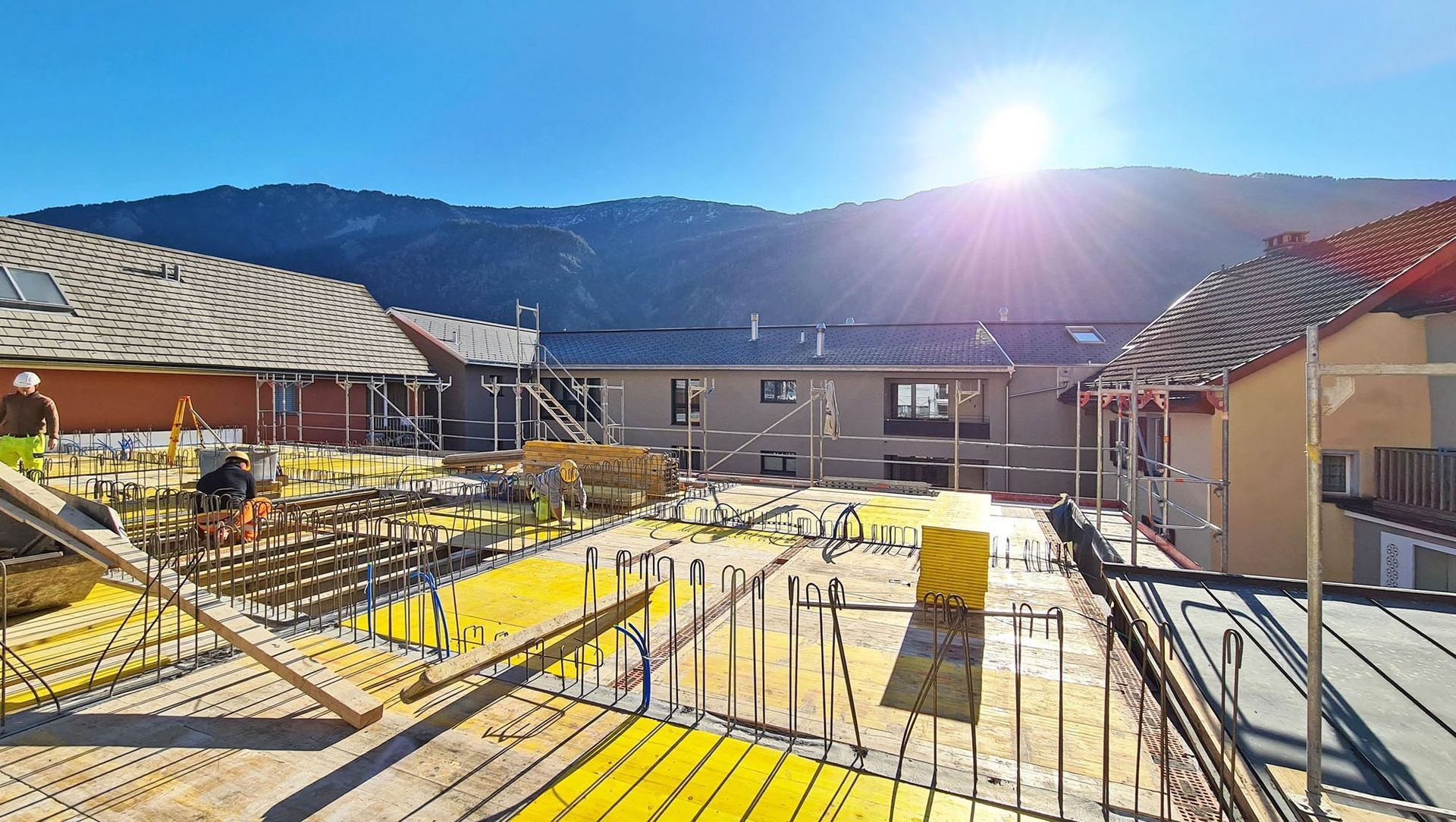 Ein im Bau befindliches Gebäude mit der Sonne, die im Hintergrund durch die Berge scheint.